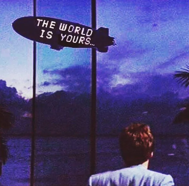 Blimp with the words "The world is yours" flying over a city at dusk
